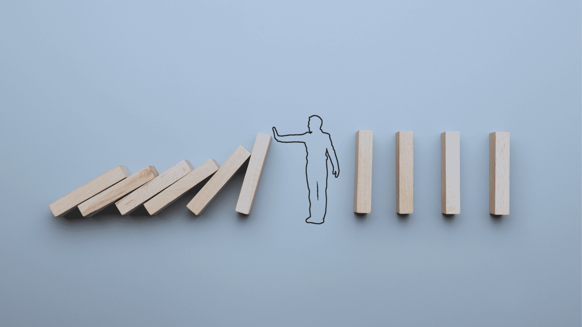 Wooden blocks arranged in a line with one block knocked over, symbolizing a person, on a light blue background.